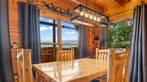 A wooden interior with a dining table, chairs, and a hanging light fixture. - Incredible MTN Views*Hot Tub + Game Room*Fireplace (Pigeon Forge)