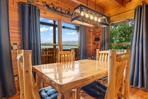 A wooden interior with a dining table, chairs, and a hanging light fixture. - Incredible MTN Views*Hot Tub + Game Room*Fireplace (Pigeon Forge)
