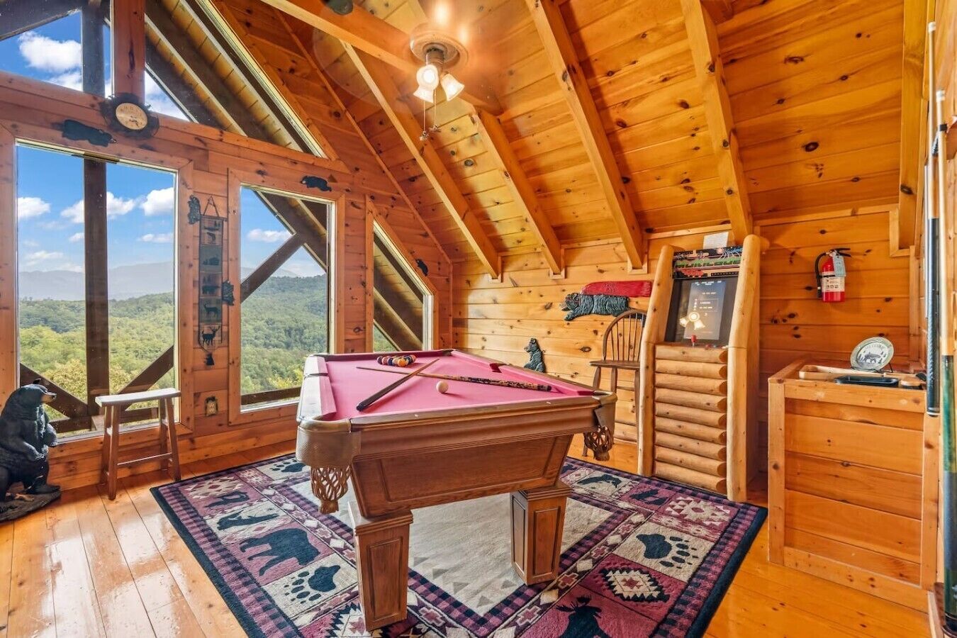 A wooden cabin with a pool table, a fire extinguisher, and a scenic view.