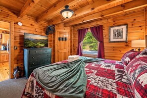 A wooden cabin bedroom with a bed, dresser, and a painting of a landscape. - Incredible MTN Views*Hot Tub + Game Room*Fireplace (Pigeon Forge)