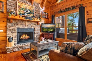A cozy cabin interior with a stone fireplace, a television, and a comfortable seating area. - Incredible MTN Views*Hot Tub + Game Room*Fireplace (Pigeon Forge)