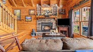 A cozy cabin interior with a stone fireplace, wooden walls, and a comfortable seating area. - Incredible MTN Views*Hot Tub + Game Room*Fireplace (Pigeon Forge)