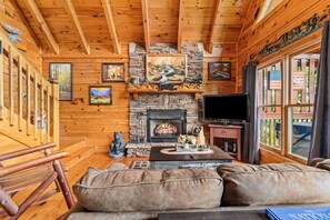 A cozy cabin interior with a stone fireplace, wooden walls, and a comfortable seating area. - Incredible MTN Views*Hot Tub + Game Room*Fireplace (Pigeon Forge)