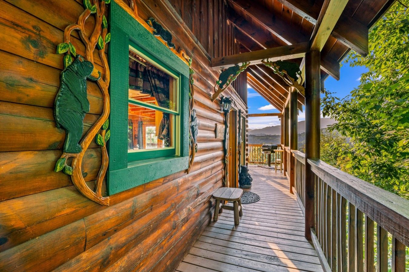 Una cabaña de madera con un porche cubierto, una ventana con detalles verdes y vistas al exterior.