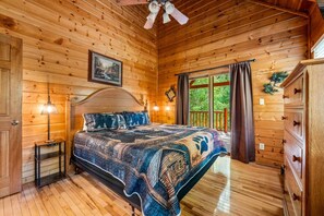 A wooden cabin bedroom with a bed, a nightstand, a dresser, and a ceiling fan. - Peaceful 2BR w/Hot Tub*Game Room*Fireplace*Quiet! (Sevierville)