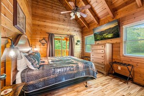 Une chambre dans une cabane en bois, avec un lit, une commode et un ventilateur de plafond.