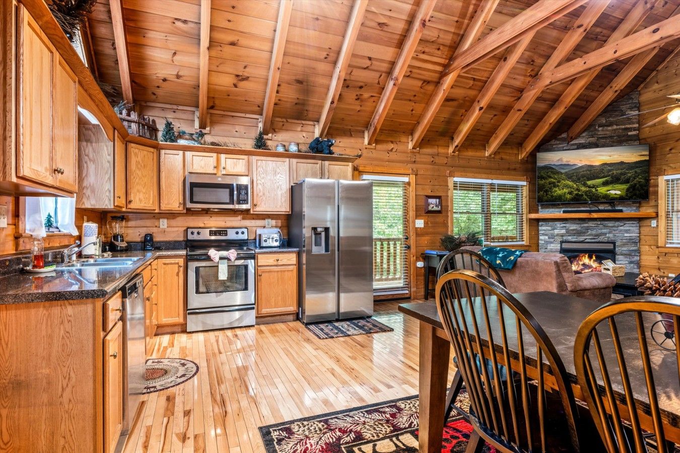 A cabin interior with a kitchen, dining area, and fireplace.