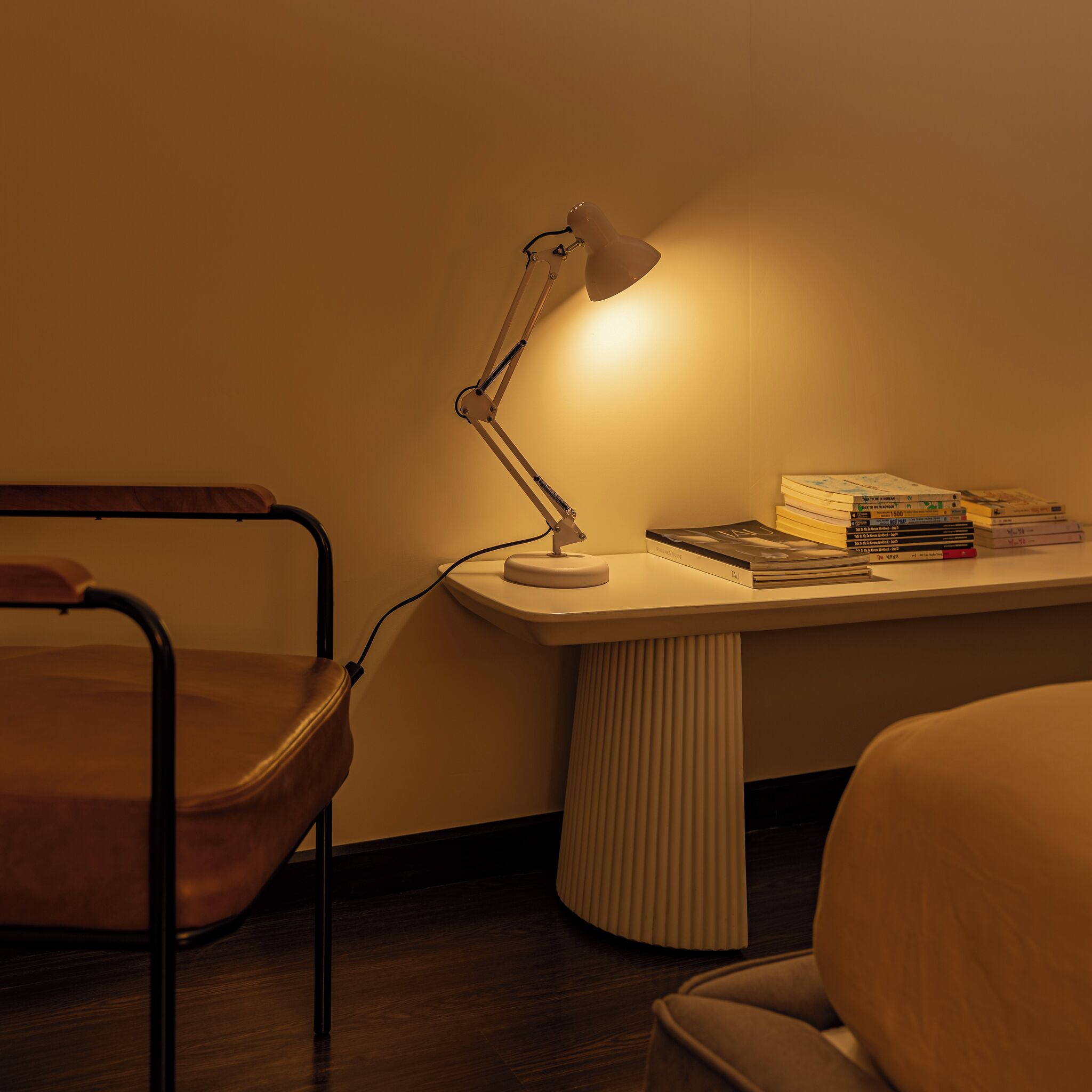 A desk with a lamp, a chair, and a stack of books.