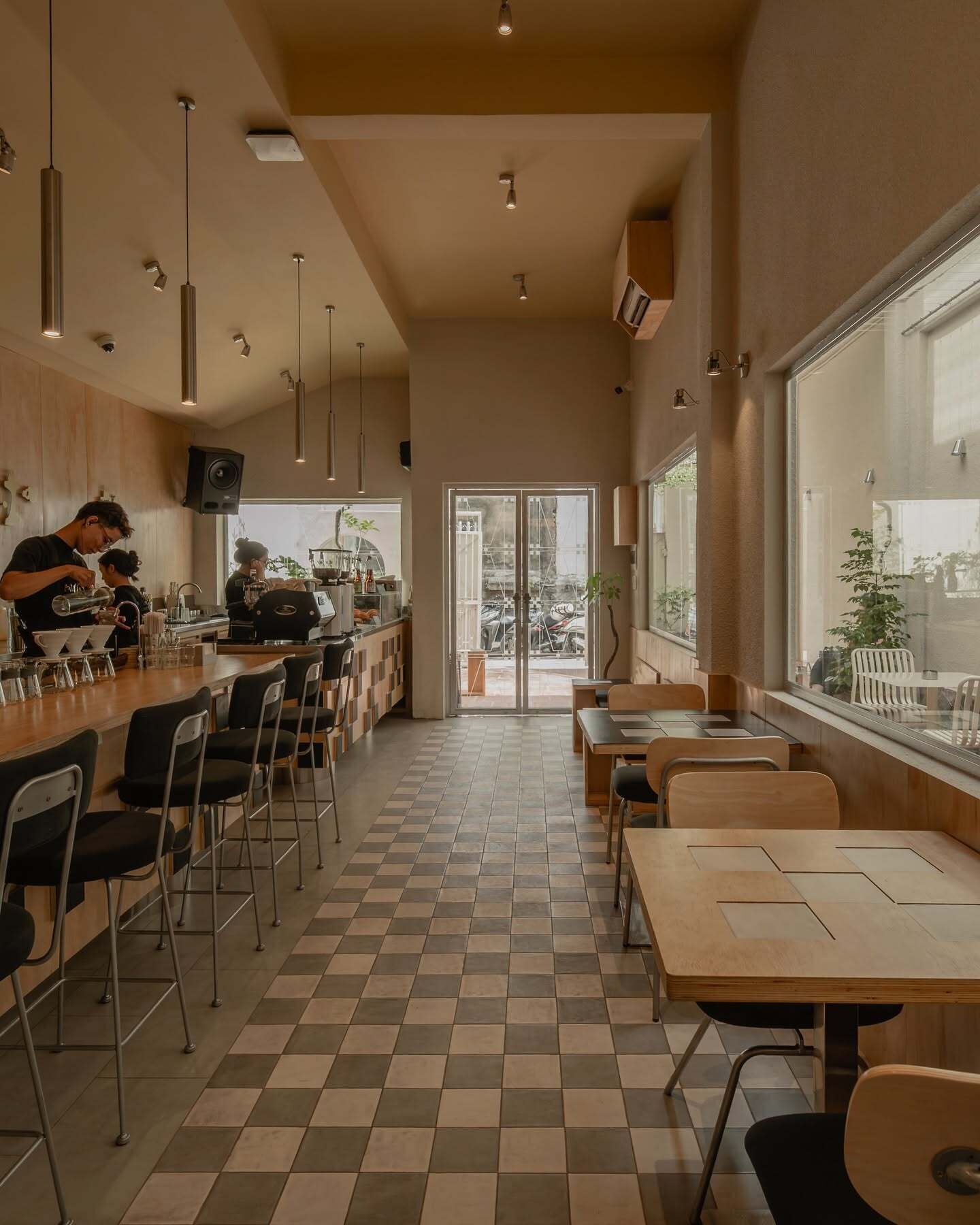 A cafe interior with a bar area, seating, and a view through the glass doors.
