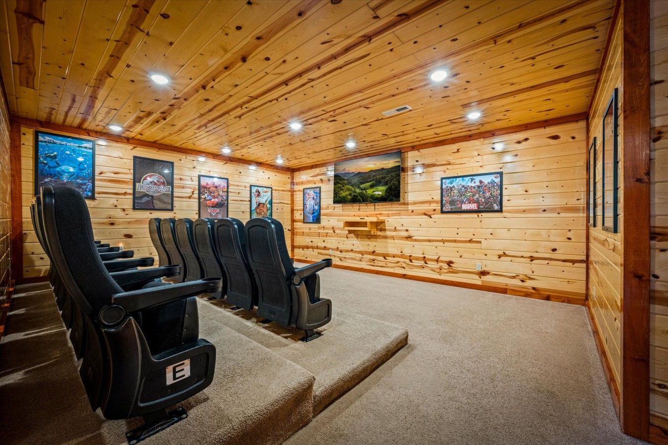 A cinema room with wooden walls, multiple black cinema seats, and a screen displaying a movie.