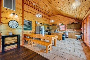 Un intérieur en bois comprenant une cuisine, un coin repas et une horloge au mur.