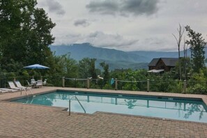 Ein Pool mit Liegestühlen und Blick auf Berge.