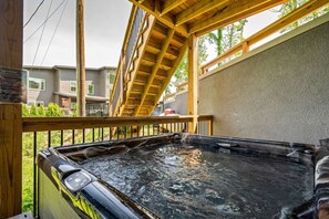 Tinaco de hidromasaje en una terraza de madera con vista a casas vecinas.