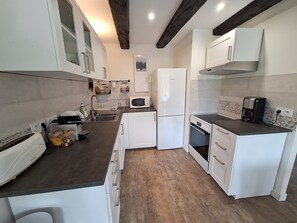 A compact kitchen with white appliances, a built-in oven, and a coffee maker. - Cosy cottage • Baie du Mont‑Saint‑Michel • Entre terre, baie & mer (Sougeal)