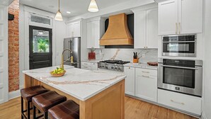 A modern kitchen with white cabinetry, a central island, a gas stove, and stainless steel appliances. - Luxurious curated high end oasis (Cincinnati)