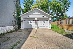 A white garage with two doors, a small porch, and a wooden fence. - Luxurious curated high end oasis (Cincinnati)