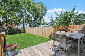 A backyard with a wooden deck, a table and chairs, a wooden fence, and a lawn. - Luxurious curated high end oasis (Cincinnati)
