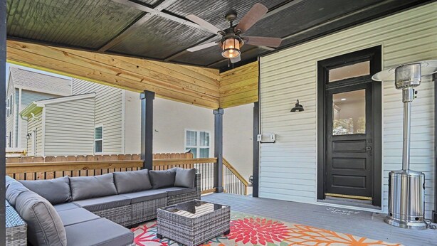 A covered porch with a gray sectional sofa, wicker coffee table, and a colorful rug. - Luxurious curated high end oasis (Cincinnati)
