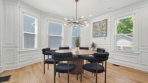 A dining room with a round table and six chairs, white walls, and a ceiling light fixture. - Luxurious curated high end oasis (Cincinnati)