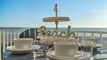 Una mesa dispuesta con tazas y platillos blancos, un vaso y un letrero decorativo con la palabra 'Beach' y una cita.