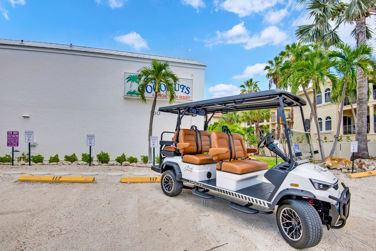 A golf cart parked in front of a building with palm trees.