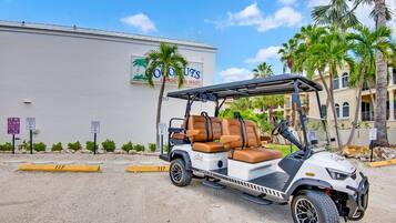 A golf cart parked in front of a building with palm trees.