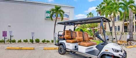 A golf cart parked in front of a building with palm trees.
