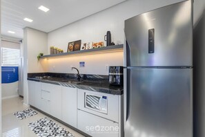 A modern kitchen with a stainless steel refrigerator, a built-in oven, and a coffee maker on the countertop. - Cars Apt 400m From Beto Carrero Obp0201 (Penha)