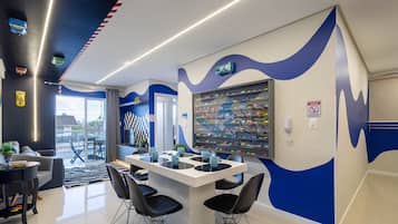 A modern interior with a dining area, chairs, a table, and a wall with a display of toy cars.