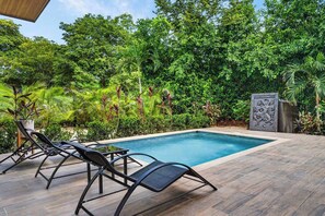 A swimming pool with lounge chairs and a stone sculpture, surrounded by lush greenery. - Modern Villa, Pool, Nature & Beach (Matapalo, Cabo Velas)
