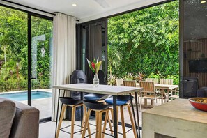 A modern outdoor dining area with a pool, surrounded by lush greenery. - Modern Villa, Pool, Nature & Beach (Matapalo, Cabo Velas)