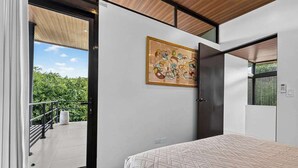Un dormitorio con cama, puerta, ventana y un cuadro en la pared.