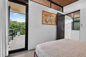 A bedroom with a bed, a door, a window, and a painting on the wall. - Modern Villa, Pool, Nature & Beach (Matapalo, Cabo Velas)