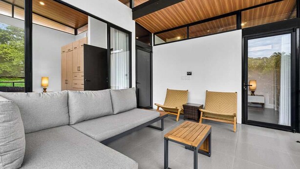 Una sala moderna con un sofá modular, dos sillones, una mesa de centro y techo de madera.