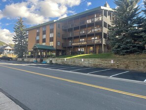 Ein mehrstöckiges Hotel mit einer grünen Markise, einem Schild mit der Aufschrift 'Crested Butte Sports' und einem Parkplatz mit gekennzeichneten Stellplätzen.