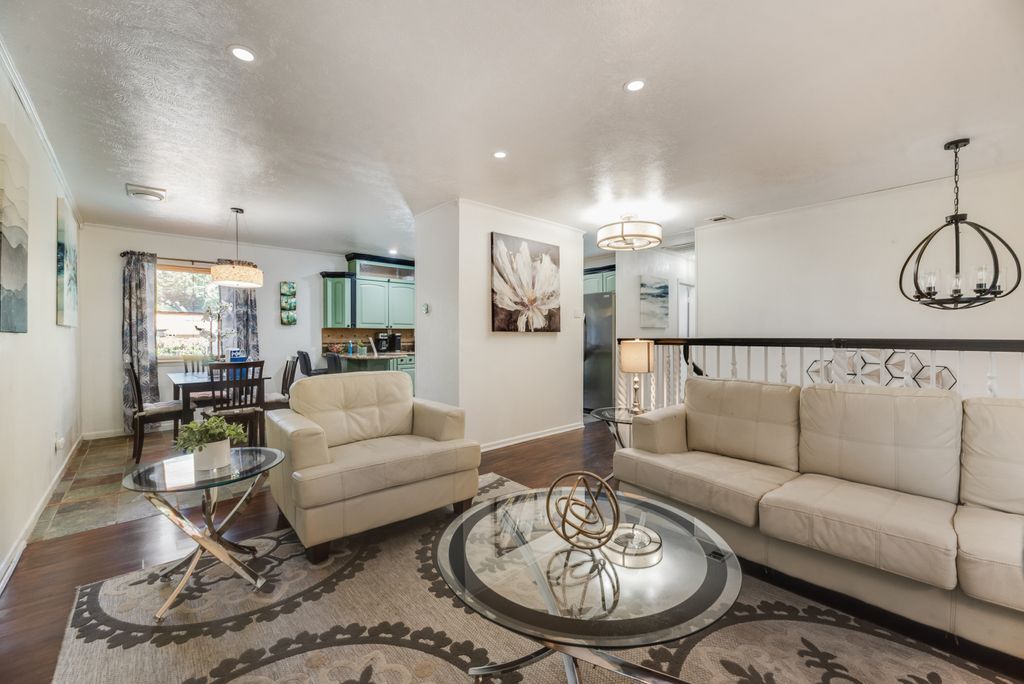 A spacious living room with a sofa, a glass coffee table, and a dining area in the background.
