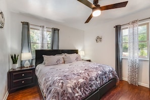 A bedroom with a bed, nightstands, a ceiling fan, and curtains. - I129 - 3BD Pool Retreat | Fire Pit & Backyard | Irving (Irving)