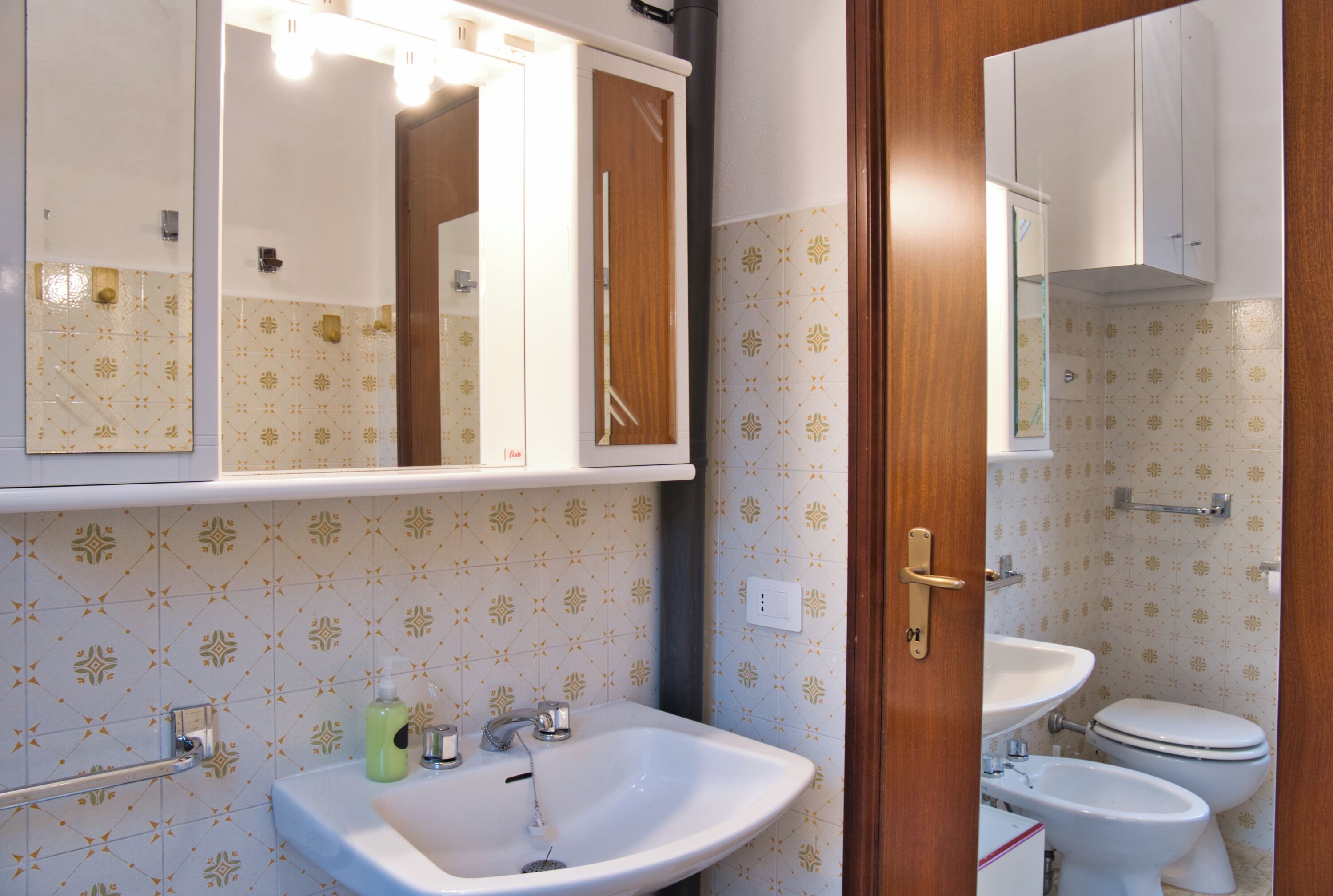 Ein Badezimmer mit Waschbecken, Spiegel und Toilette.