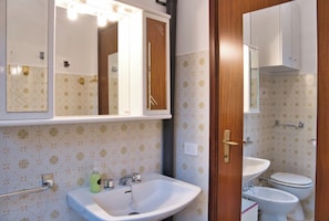 Een badkamer met een wit wastafel, een spiegel en een toilet.