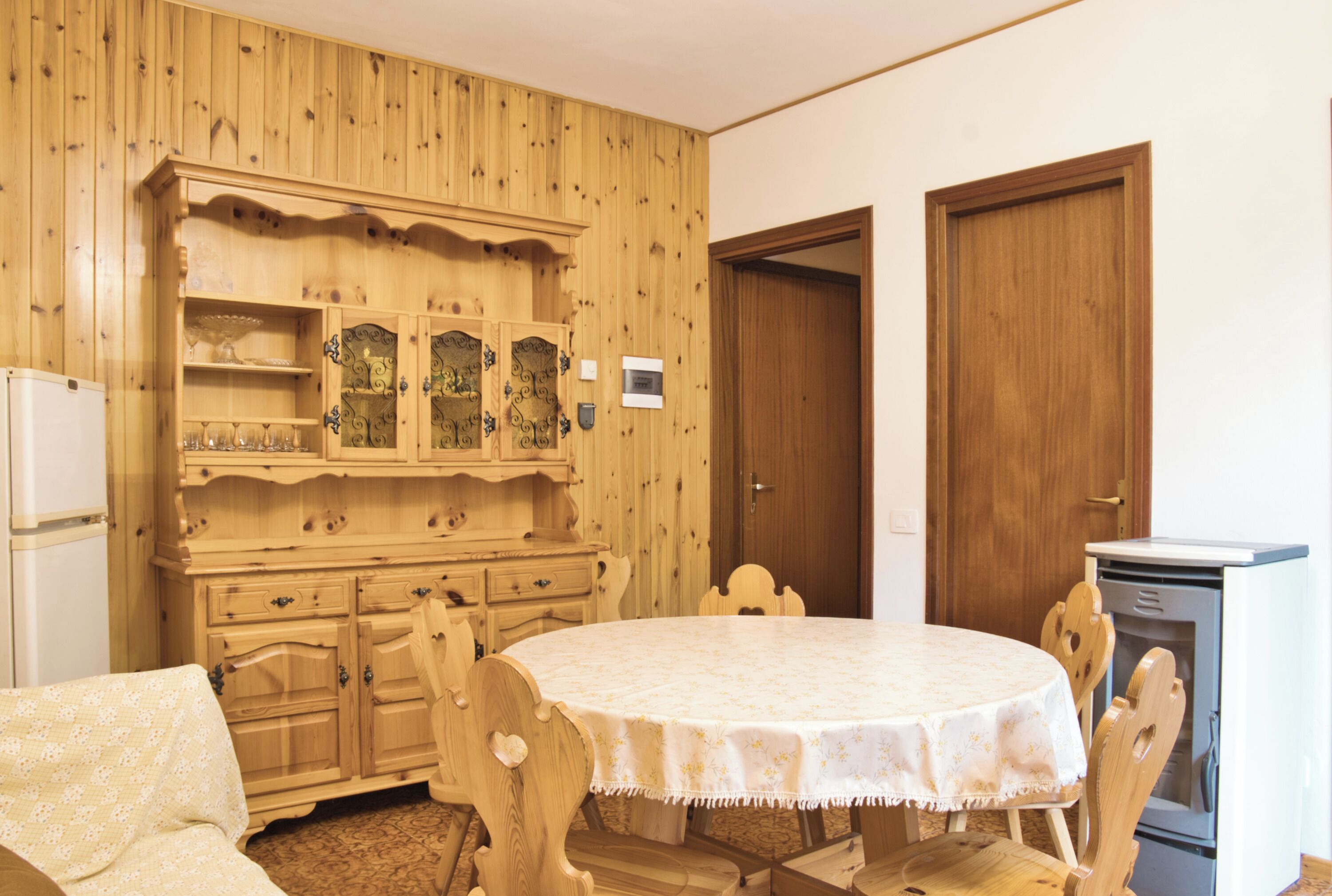 Una habitación con una mesa redonda, armarios de madera y un microondas.