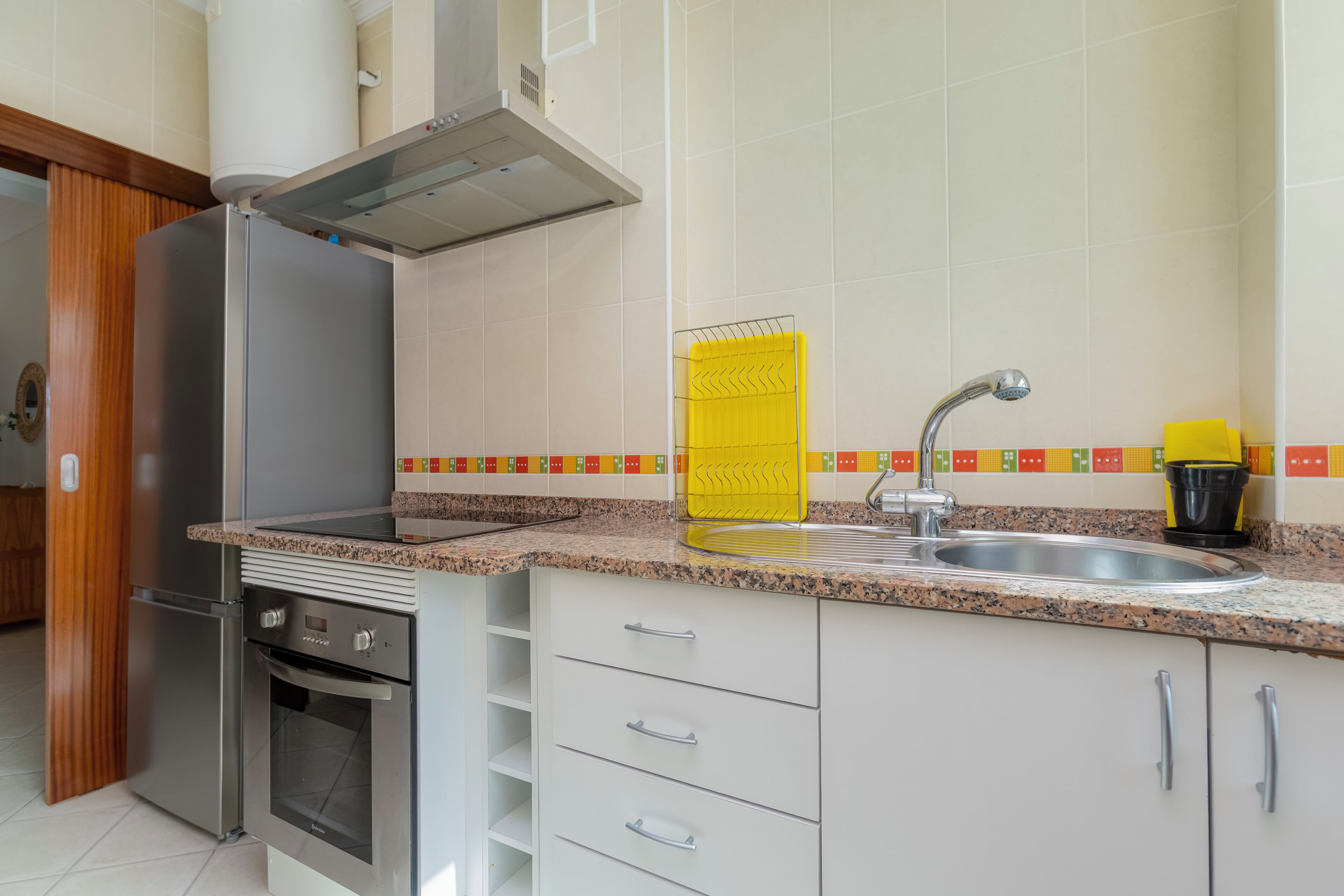 A kitchen with a stainless steel refrigerator, oven, and a modern faucet.