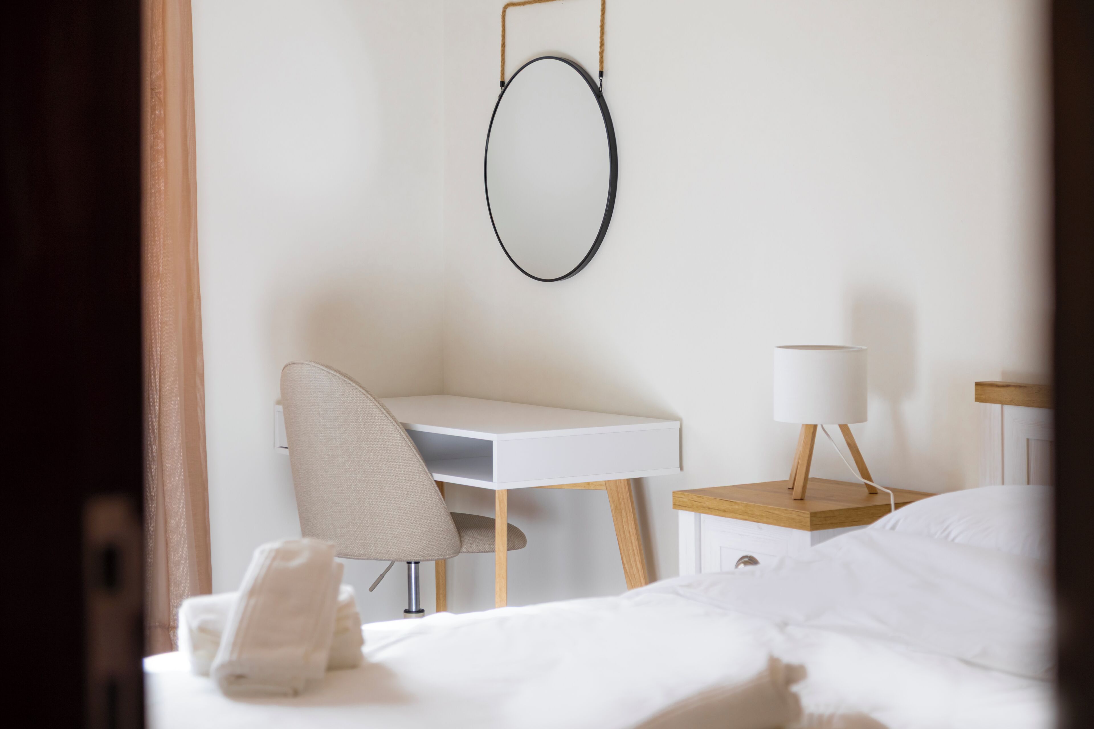 A hotel room with a bed, a desk, a chair, a lamp, and a towel on the bed.