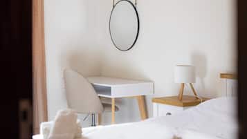 A hotel room with a bed, a desk, a chair, a lamp, and a towel on the bed.