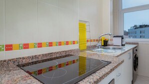 A modern kitchen with a built-in stove, a sink, and a window overlooking a cityscape. - Sea Breeze Apartment - D. Ana Beach (Lagos)