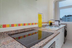 Eine moderne Küche mit Einbauherd, Spüle und Fenster mit Blick auf eine Stadtlandschaft.