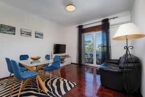 Ein modernes Wohnzimmer mit Essbereich, einem Flachbildfernseher und einer Couch.