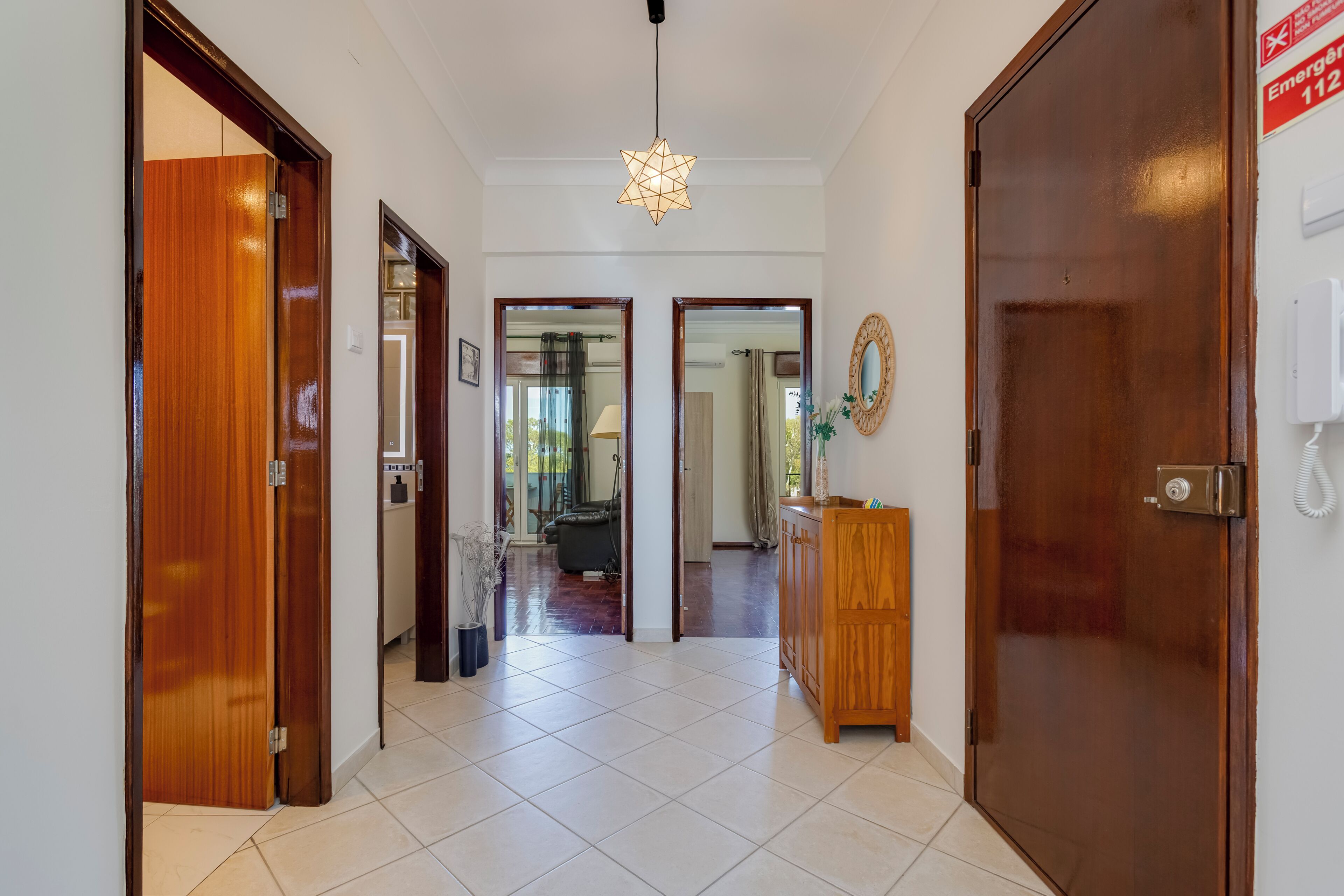 A hallway with a wooden door on the left, a wooden cabinet on the right, and a star-shaped light fixture on the ceiling.