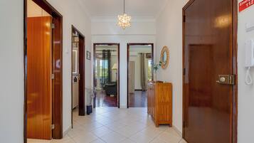 A hallway with a wooden door on the left, a wooden cabinet on the right, and a star-shaped light fixture on the ceiling.