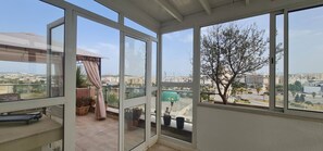Ein Balkon mit Blick auf eine Stadtansicht, einschließlich Gebäude und eines Baumes.