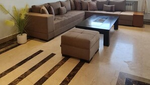 A spacious living room with a sectional sofa, a coffee table, and a potted plant. - Luxurious 3-bedroom Apartment in Heart of Tunis (Tunis)